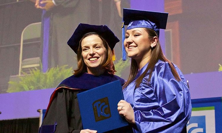 TCC President Goodson wears her doctoral rigalia and poses with TCC Graduate in Blue cap and gown.