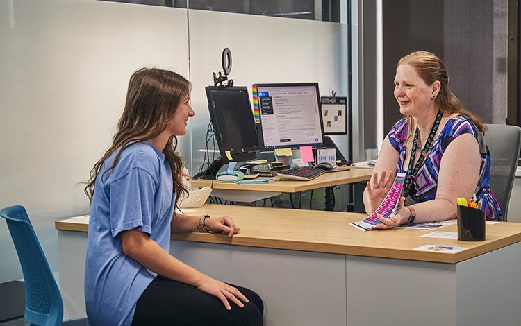 TCC student sits in front of a desk and receives help selecting courses from her academic advisor.